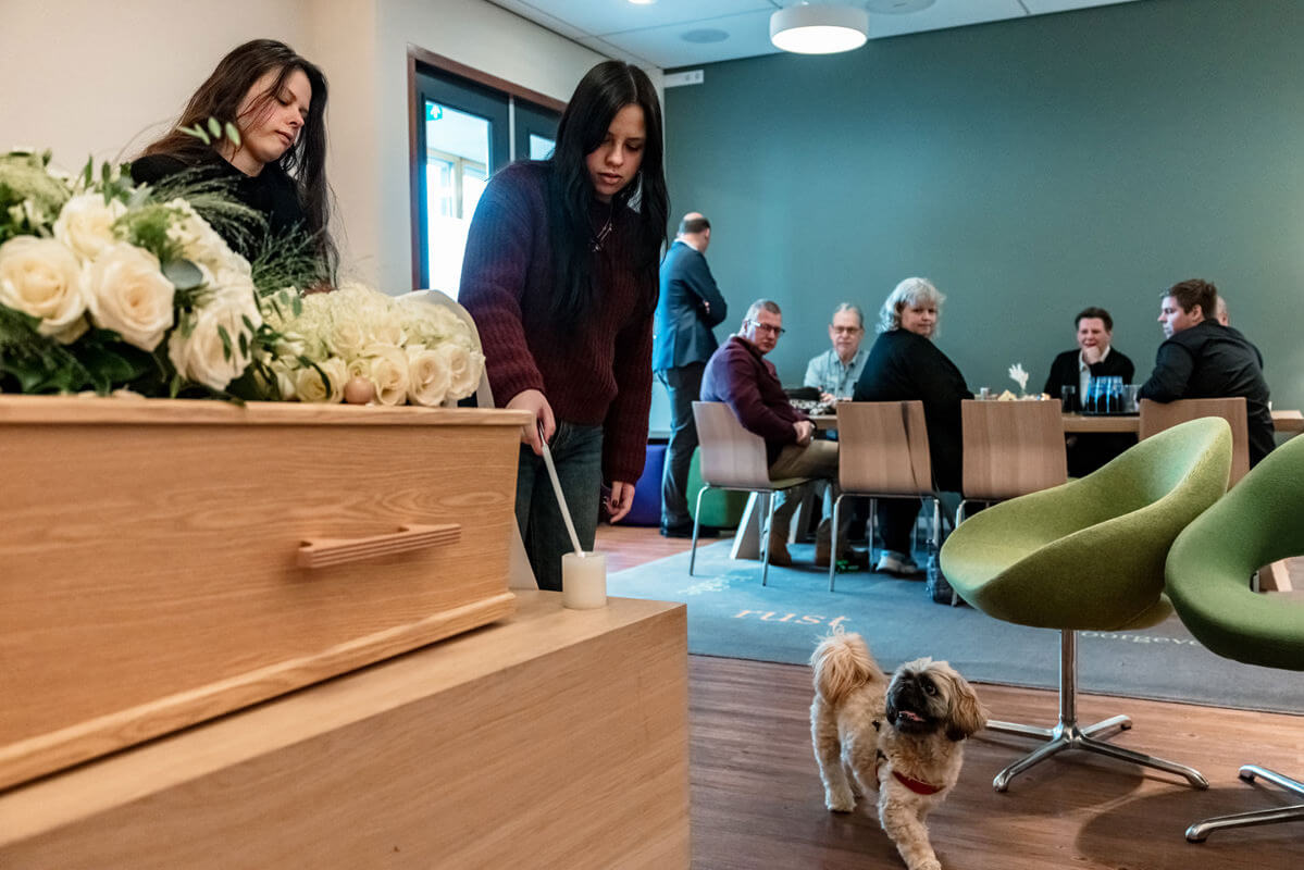hond blijft dicht bij de familie tijdens een uitvaart